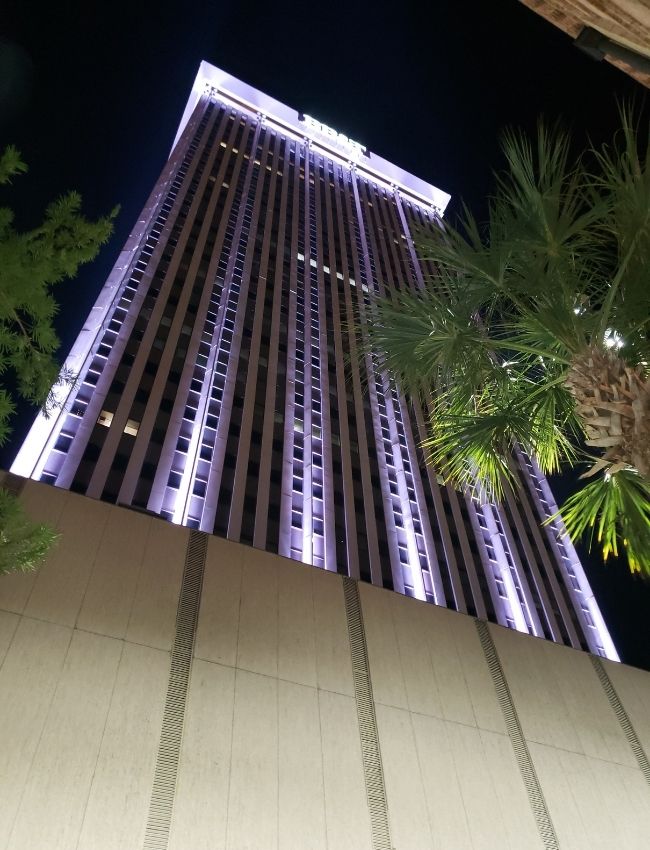A tall and glamorous facade with lights at ngiht.